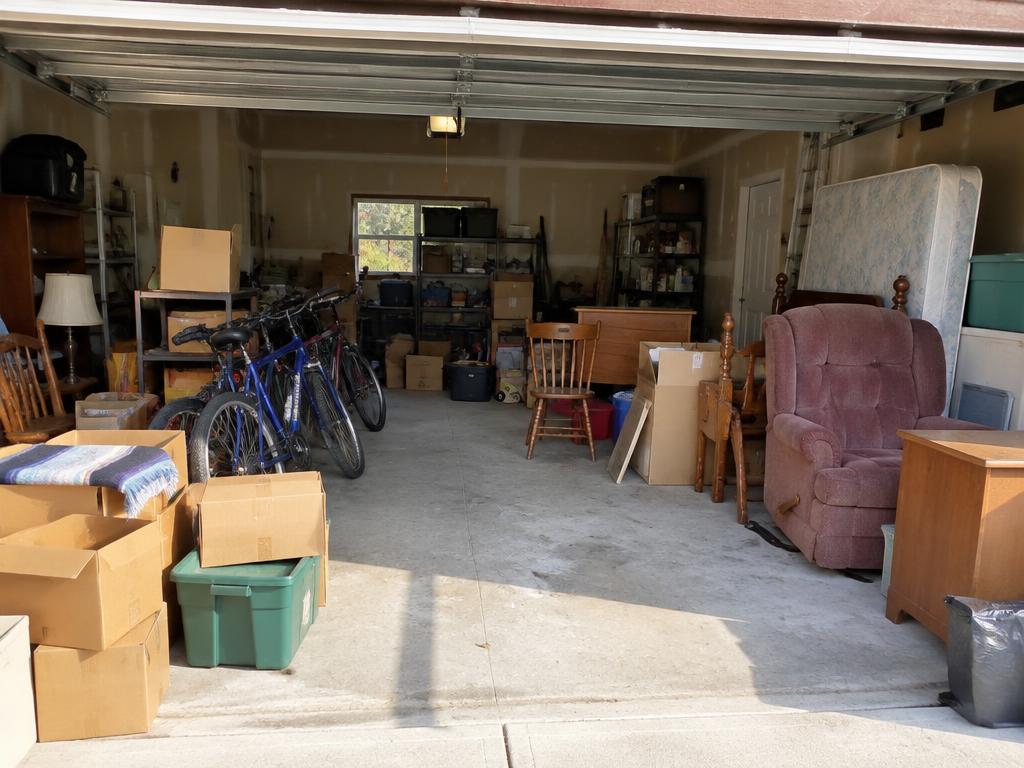 Cluttered garage full of boxes, bikes and furniture